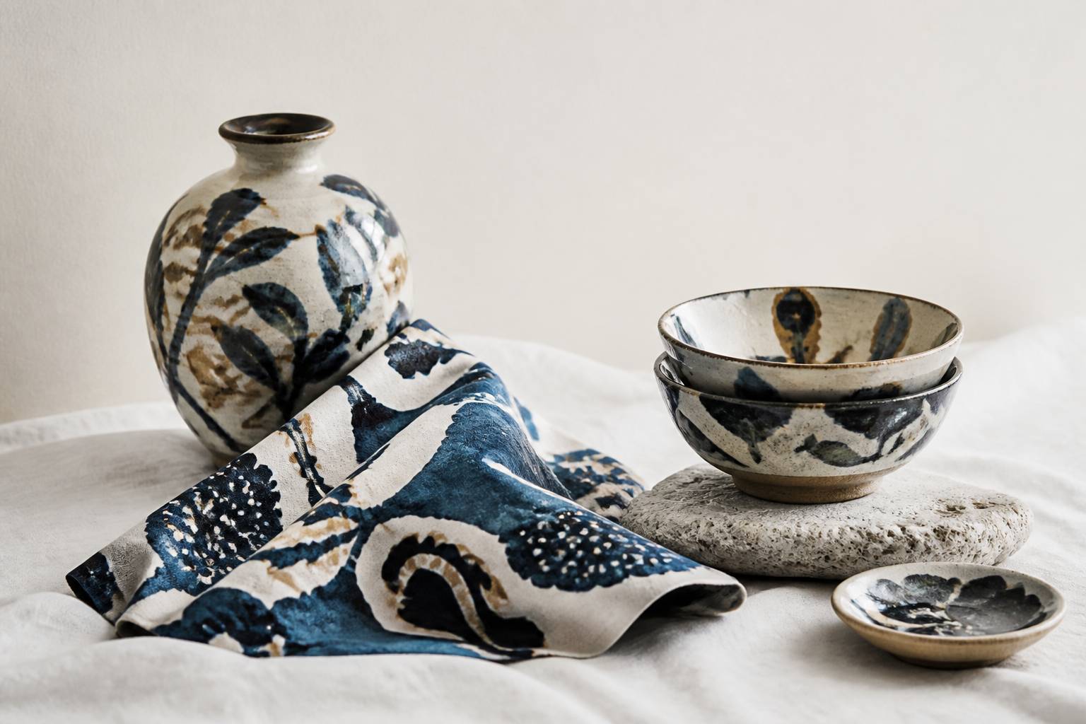 Poterie en terre cuite émaillée et tissu bingata aux motifs bleus et blancs sur un linge blanc
