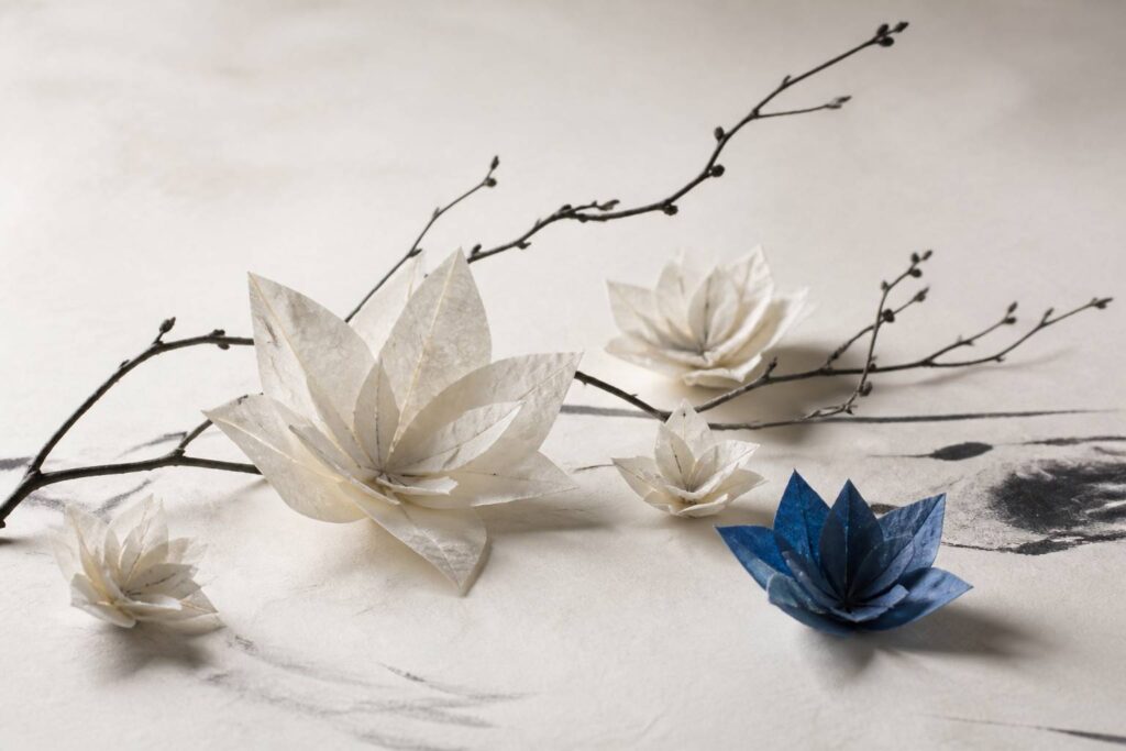 Fleurs en origami en papier blanc washi avec une fleur indigo sur une table claire