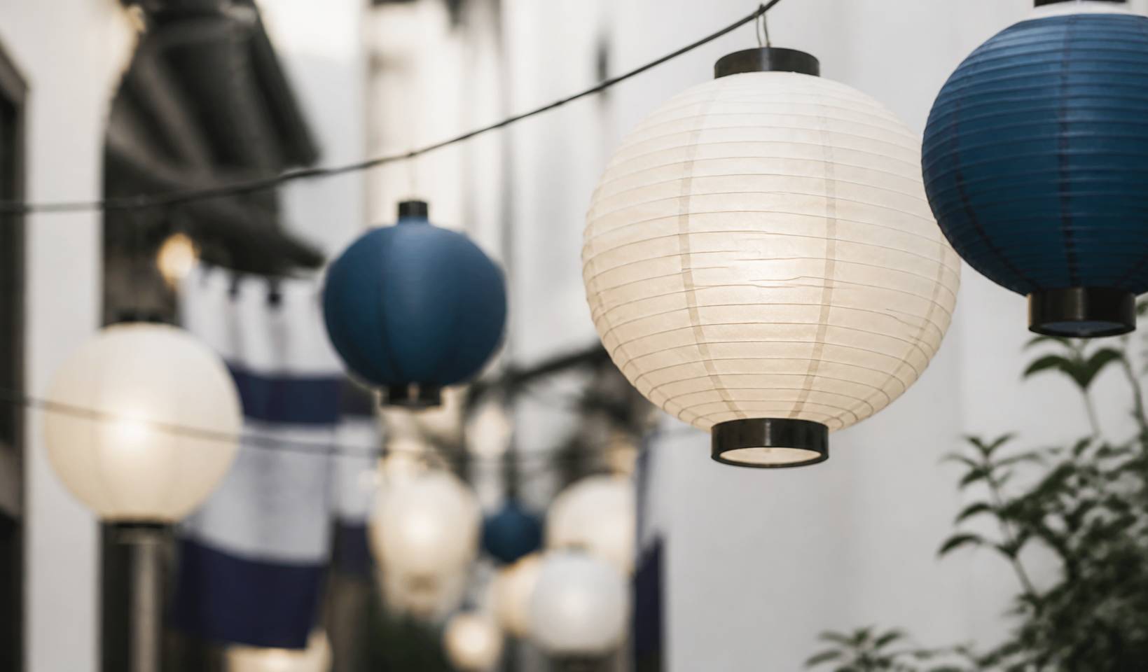 Lanternes en papier washi blanches et indigo suspendues dans une ruelle traditionnelle