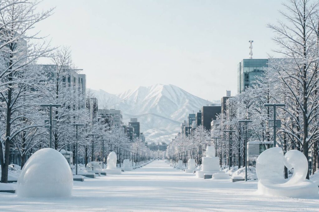 Avenue enneigée de Sapporo avec sculptures de neige du festival et montagnes d'Hokkaido