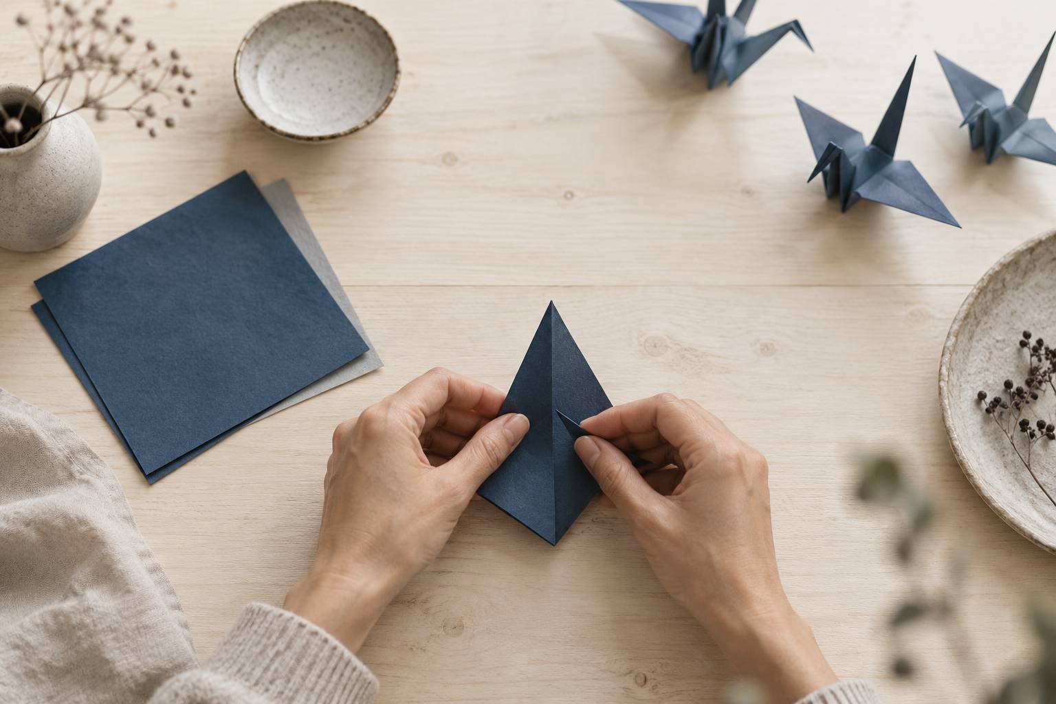 Mains anonymes pliant une grue en origami générique sur une table en bois